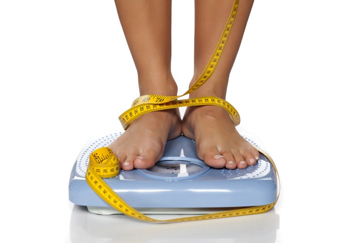 woman's feet on a domestic weight scale and measuring tape around them